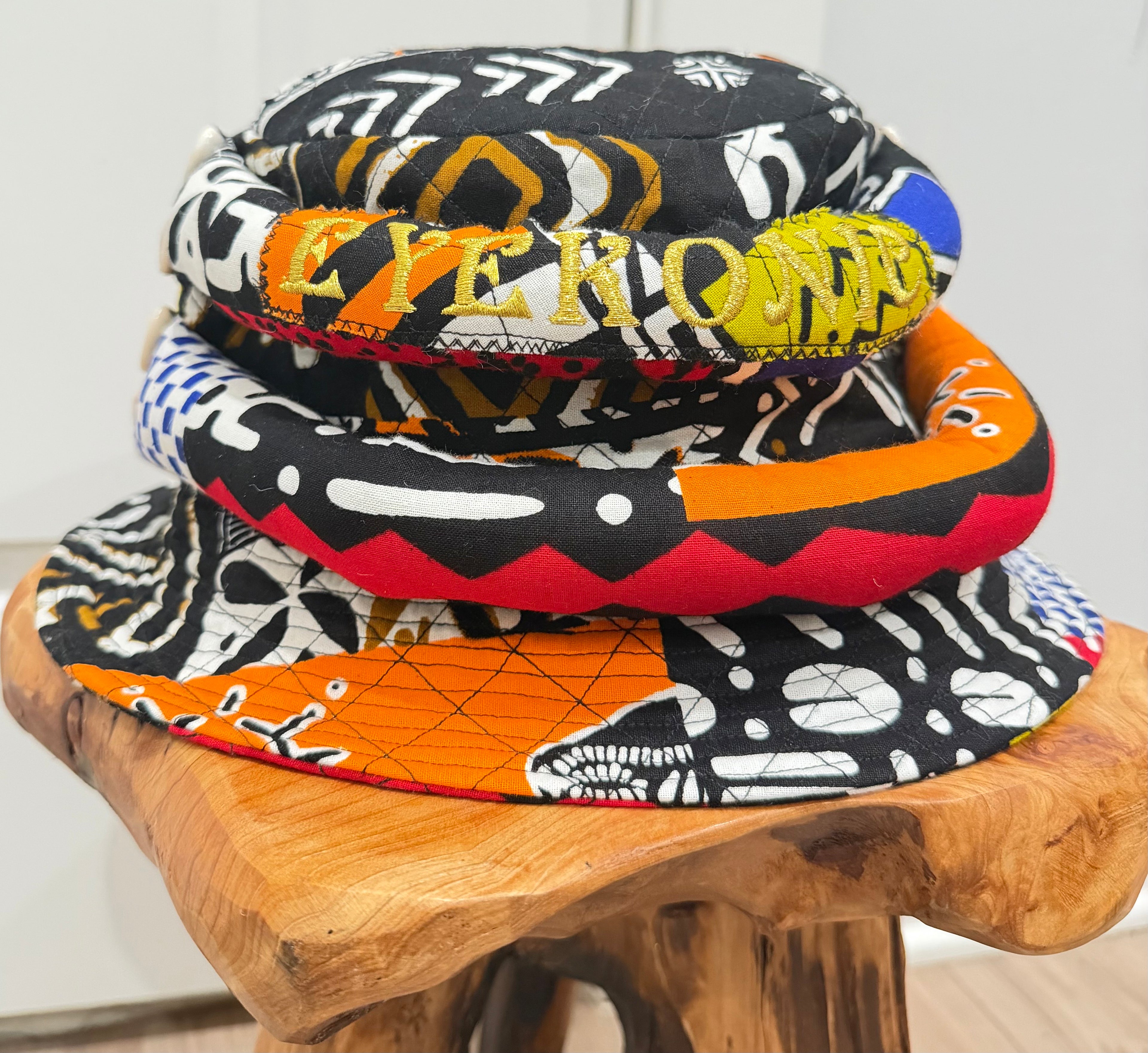 Stack of colorful bucket hats on a wooden stool with a white background