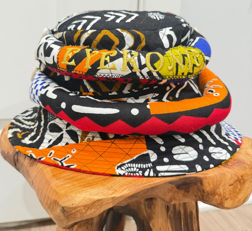 Stack of colorful bucket hats on a wooden stool with a white background