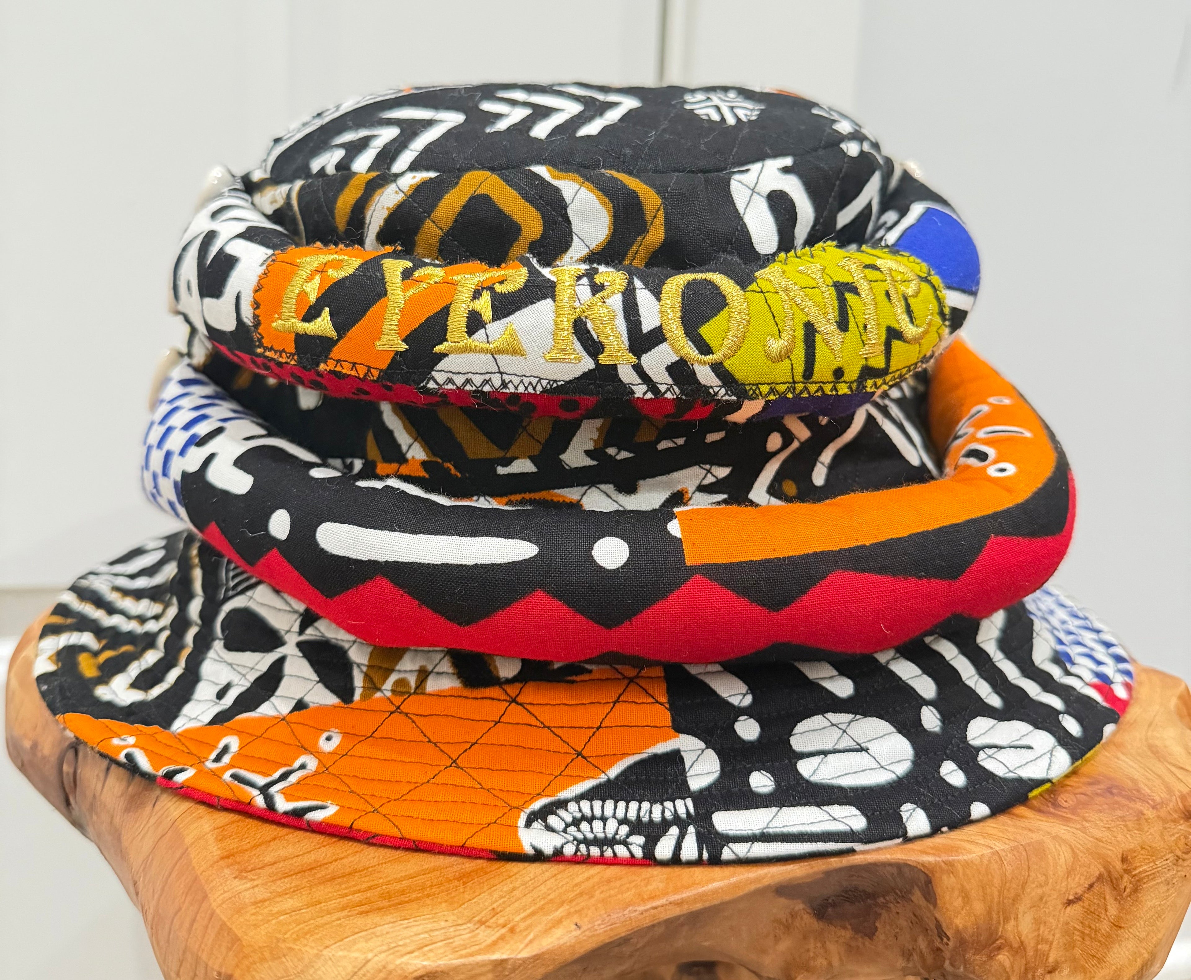 Stack of colorful patterned hats on a wooden block with a white background